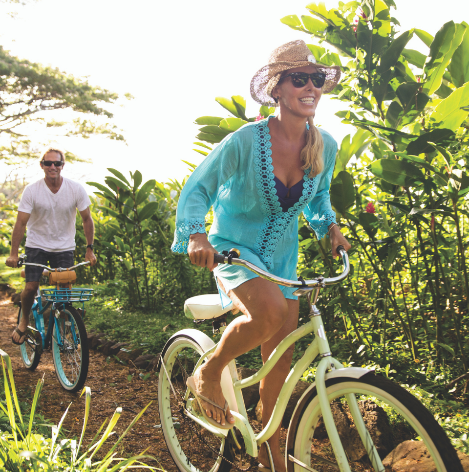 Happy couple bikes along path at Timbers Kauai.